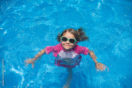 Little girl with sunglasses in a pool