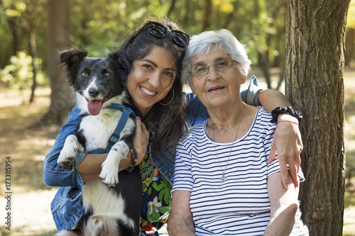 Konstfotografi happy senior woman with her granddaughter and their dog in the park