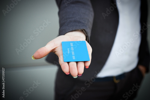 Concept of purchases, banking services. A woman in a suit and glasses points and passes a credit card. With a place for advertising text.
