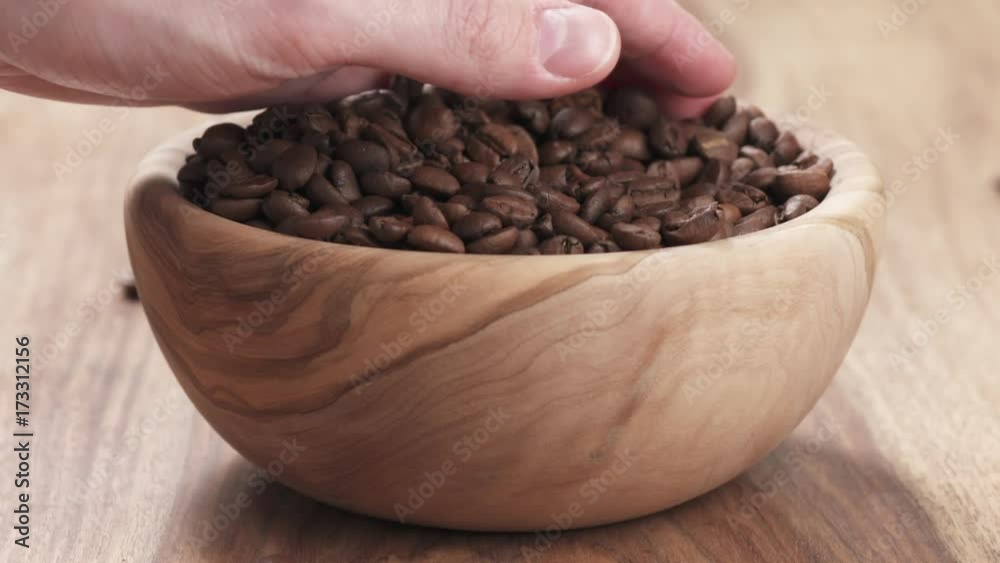 Slow motion young man hand taking some coffee beans from bowl to check quality Slow motion young man hand taking some coffee beans from bowl to check quality