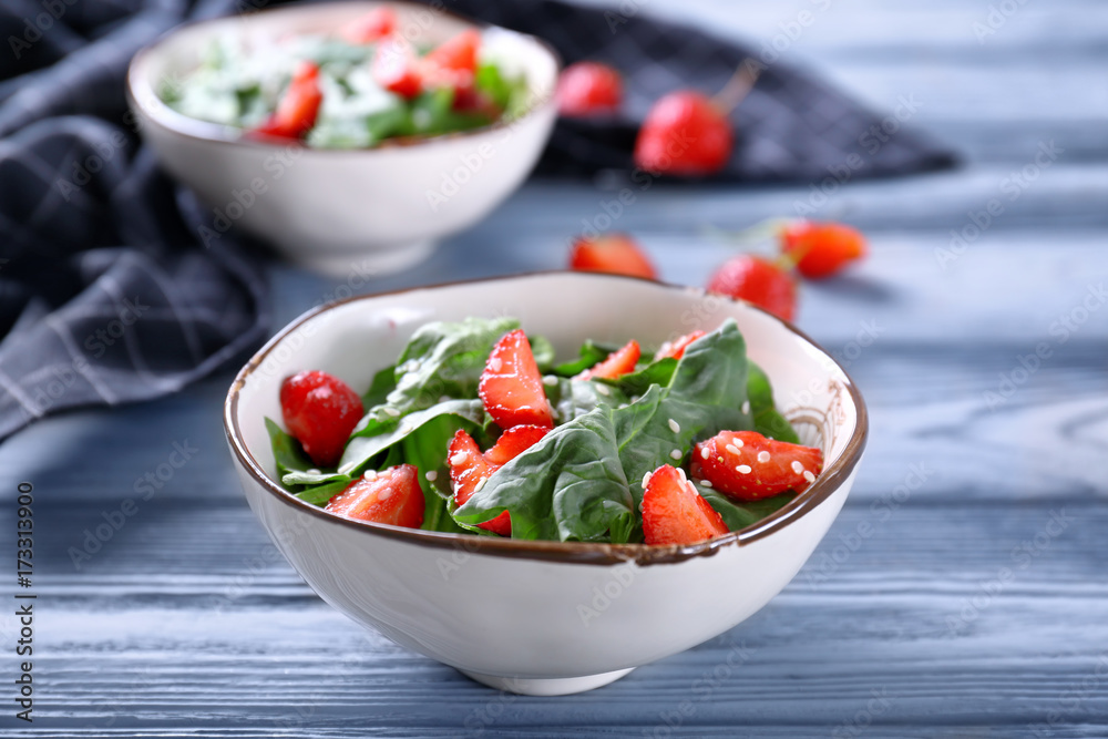 Bowl with strawberry spinach salad on wooden table Bowl with strawberry spinach salad on wooden table