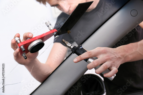 Specialist fixing crack on car windshield in repair shop