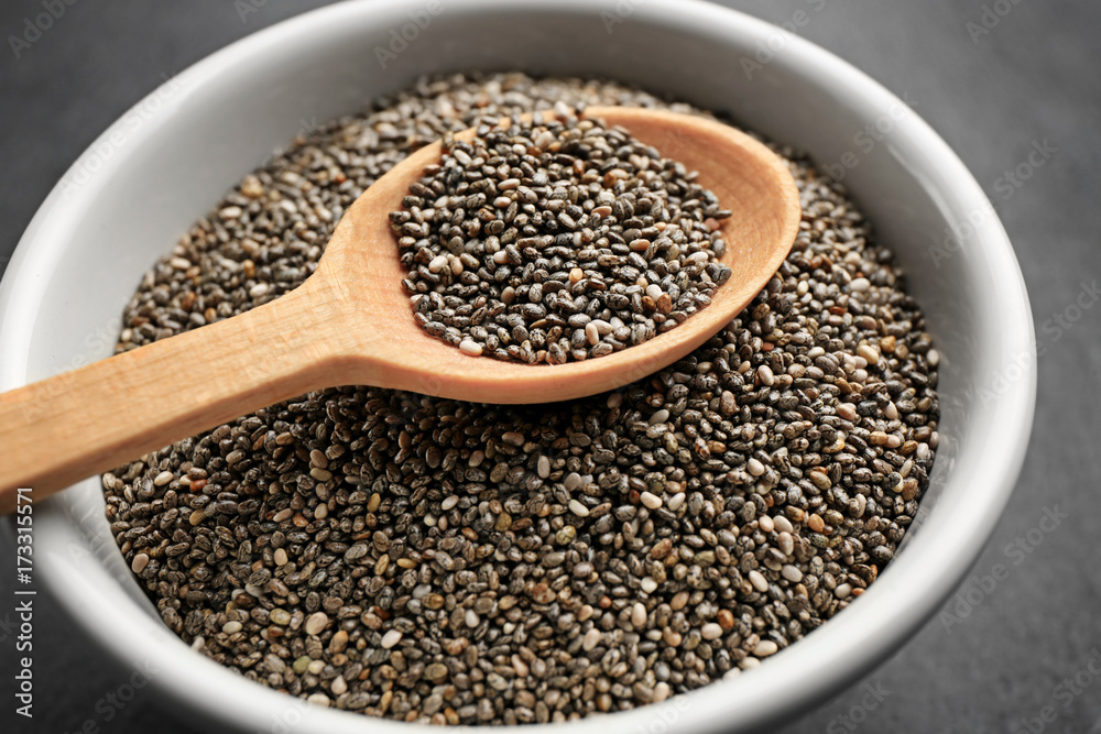 Chia seeds in wooden spoon over bowl, closeup Chia seeds in wooden spoon over bowl, closeup