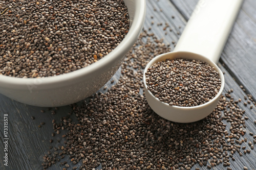 Chia seeds in scoop and bowl on table, closeup