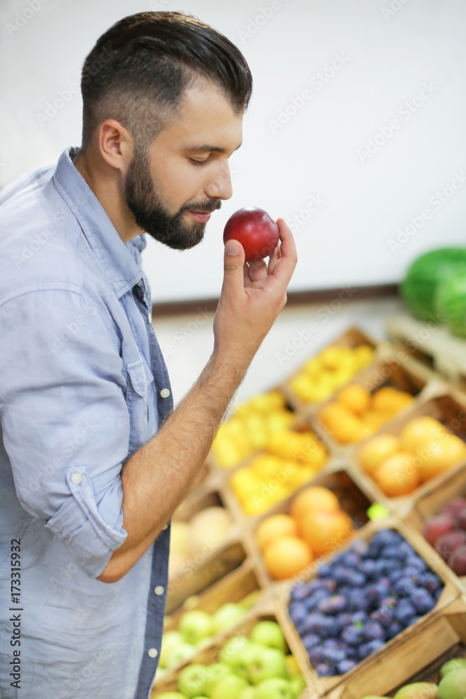 Obraz premium Young man with peach at market