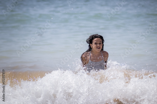 Niña morena bañándose en el mar y jugando con las olas. © Trepalio