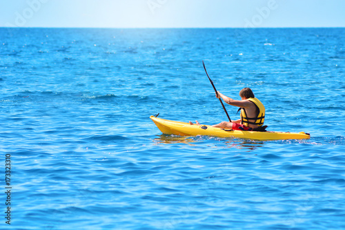 A man sails on a yellow canoe and rowing with an oar. Kayaking by the sea. © Dmytro