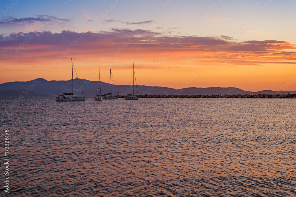 Yachts docked in marina at sunset in Naxos port. Cyclades Island, Greece.