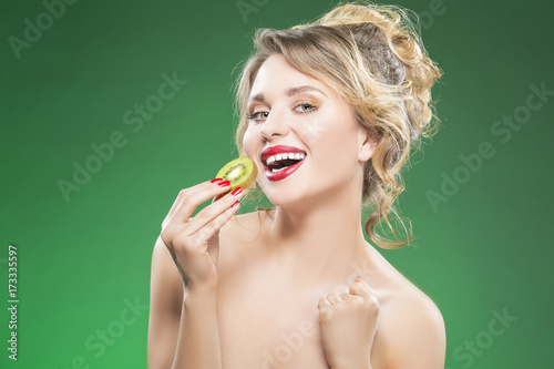 Fruit Kiwi Series. Sensual and Sexy Naked Caucasian Model with Teeth Diastema Posing With Juicy Kiwi Fruit. Against Green.