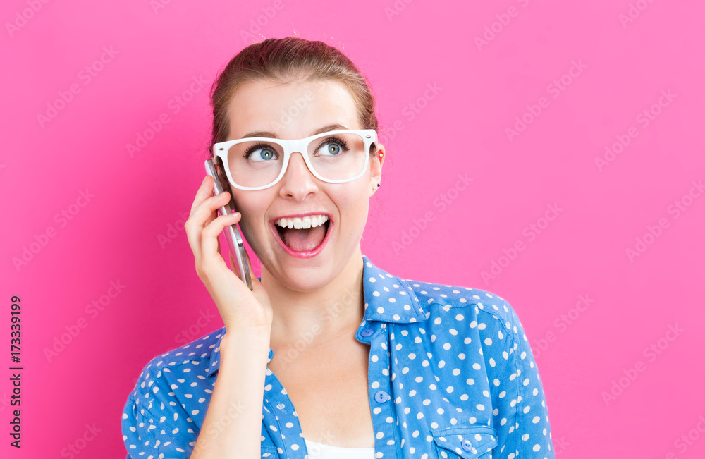 Young woman talking on the phone on a pink background Young woman talking on the phone on a pink background