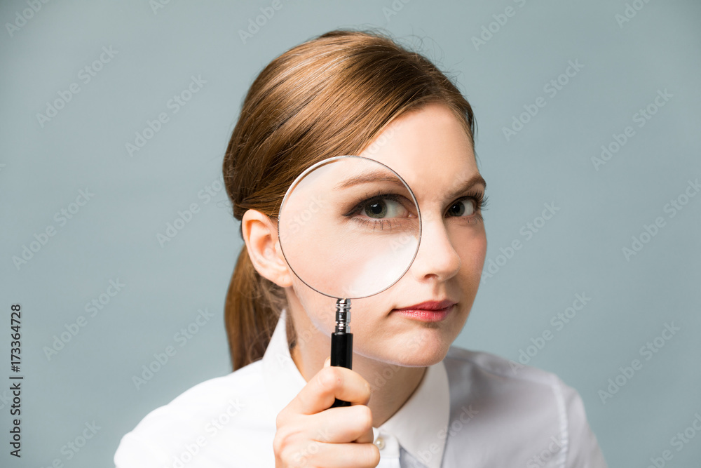 Young woman looking through a magnifying glass. Young woman looking through a magnifying glass.