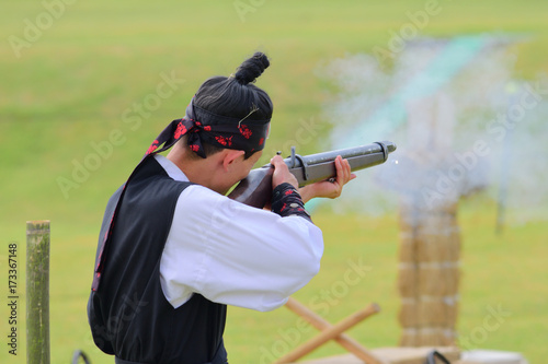 A gunman wearing a traditional korean dress and shooting a musket