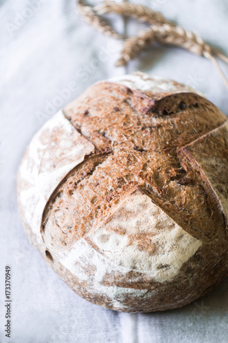Beautiful freshly baked rustic bread and ears of wheat on gray towel