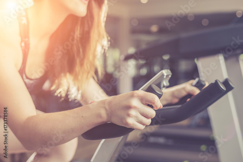 Young caucasian woman doing exercise with exercise equipment and machine in gym. Health and fitness concept. Vintage color and warm lens flare filter effect