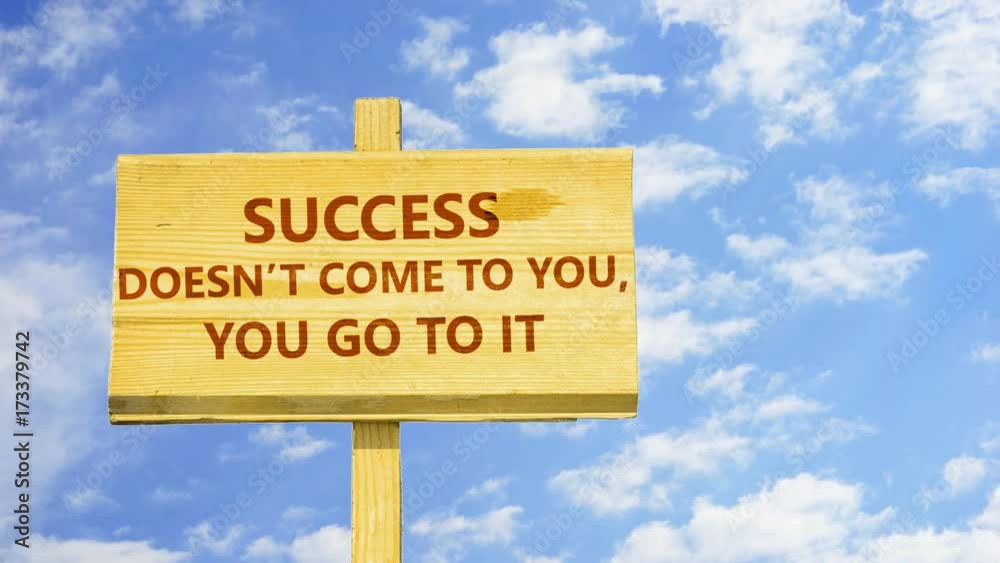 Success doesn't come to you, yo go to it. Words on a wooden sign against time lapse clouds in the blue sky.