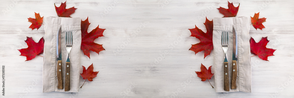 Cutlery set on wooden table with red maple leaves. Concept of healthy organic eating and thanksgiving dinner. Copy space. Wide panoramic image.