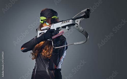 Fotografie Redhead female Biathlon champion aiming with a competitive gun.