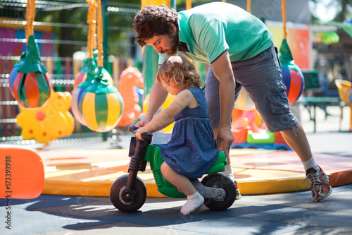 little girl playing with her father on a playground photo