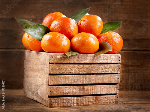 fresh mandarin oranges fruit with leaves in a wooden box