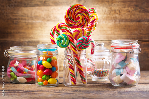 Colorful candies, jellies, lollipops, marshmallows and marmalade in a glass jars