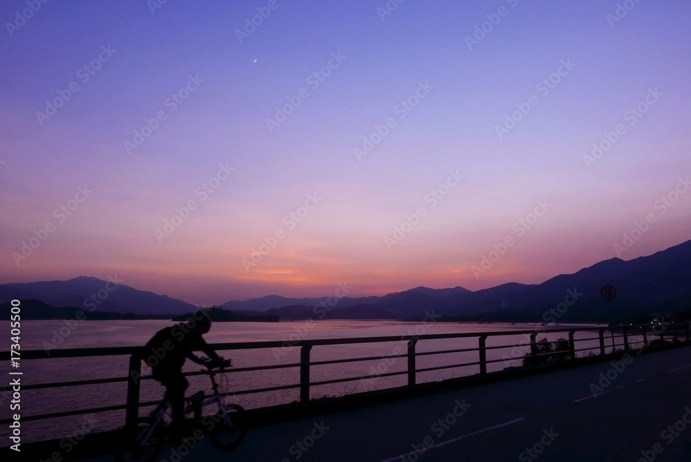 Fototapeta premium Silhouette of bicycle, fence, mountain, gradient purple sky