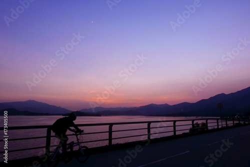 Silhouette of bicycle, fence, mountain, gradient purple sky