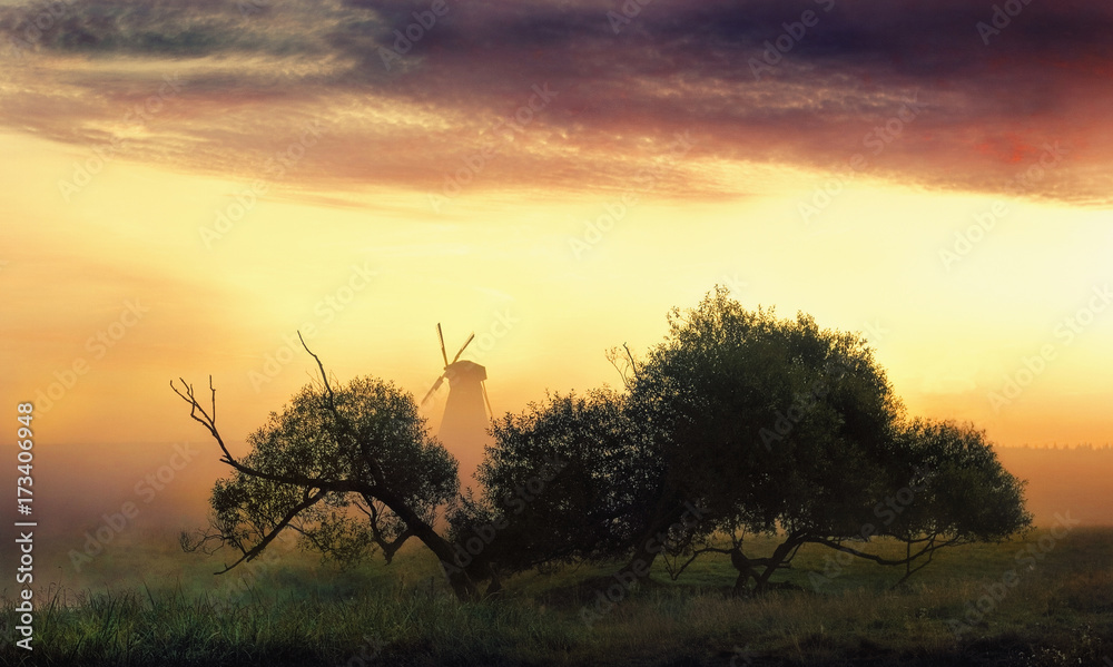 Misty morning landscape with a windmill. The Belarusian landscape, village Dudutki.