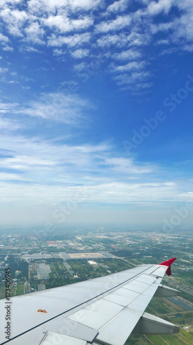 Wing of airplane, green land and blue sky