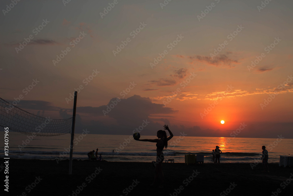 The silhouettes people at the sunset background. girl holding a ball of volleyball