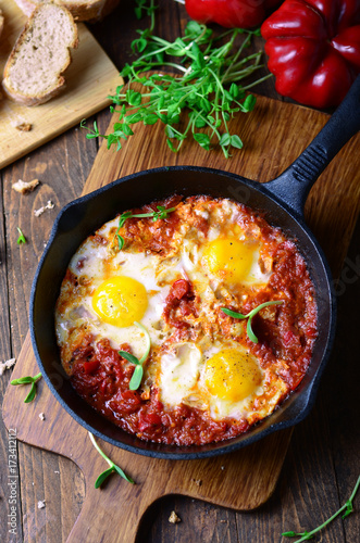 Shakshuka, Fried Eggs with Tomato Sauce in a Pan, Rustic Style and Wooden Background