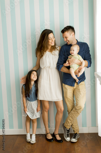 Young family with a baby and little girl standing  by the wall © BGStock72