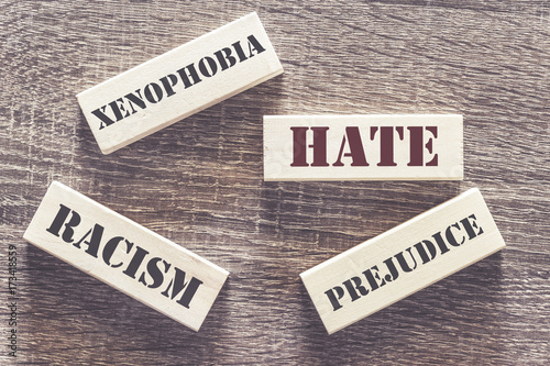 Hate, xenophobia, racism and prejudice words written with tiles on a wooden table. Social issues concept