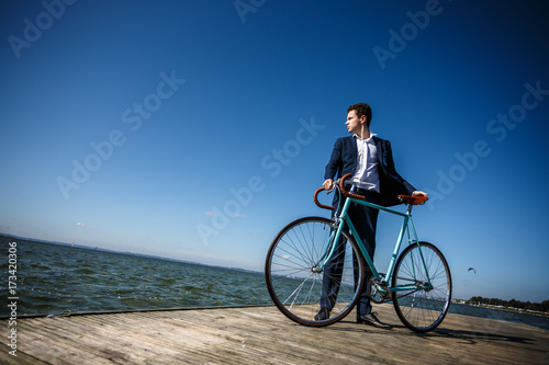 Young man standing with bike on pier 