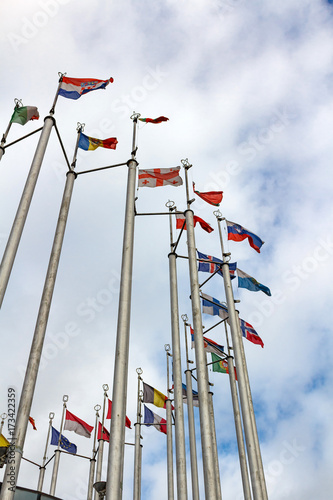 Flags of different countries on cloudy sky background