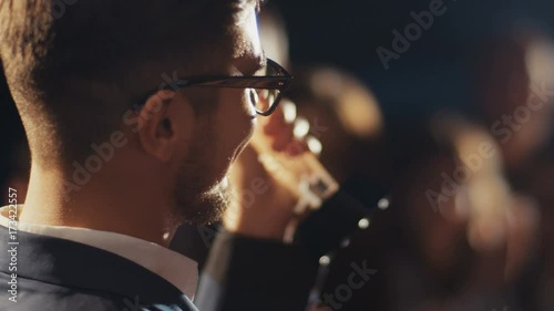 Award ceremony concept, closeup portrait of young attractive male actor on red carpet holding prize in hands, crowd people applause, celebrity photo light flashes lifestyle money fame stars winner win photo