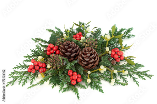 Christmas decoration with holly, ivy, mistletoe, cedar and juniper leaf sprigs and pine cones on white background.