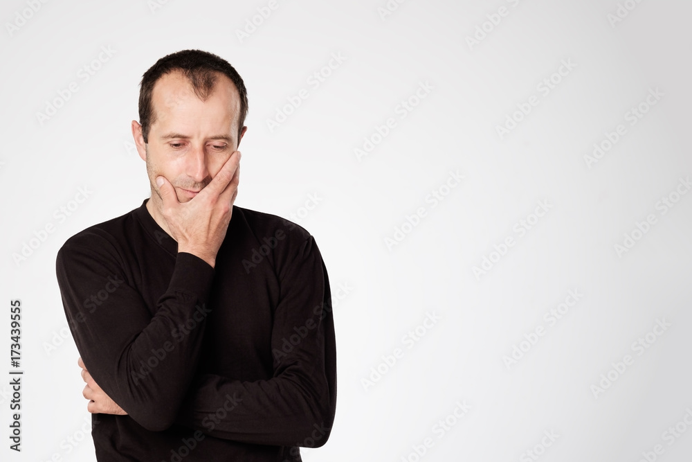 Caucasian man in black shirt looking down with skeptical emotion on face. Caucasian man in black shirt looking down with skeptical emotion on face.