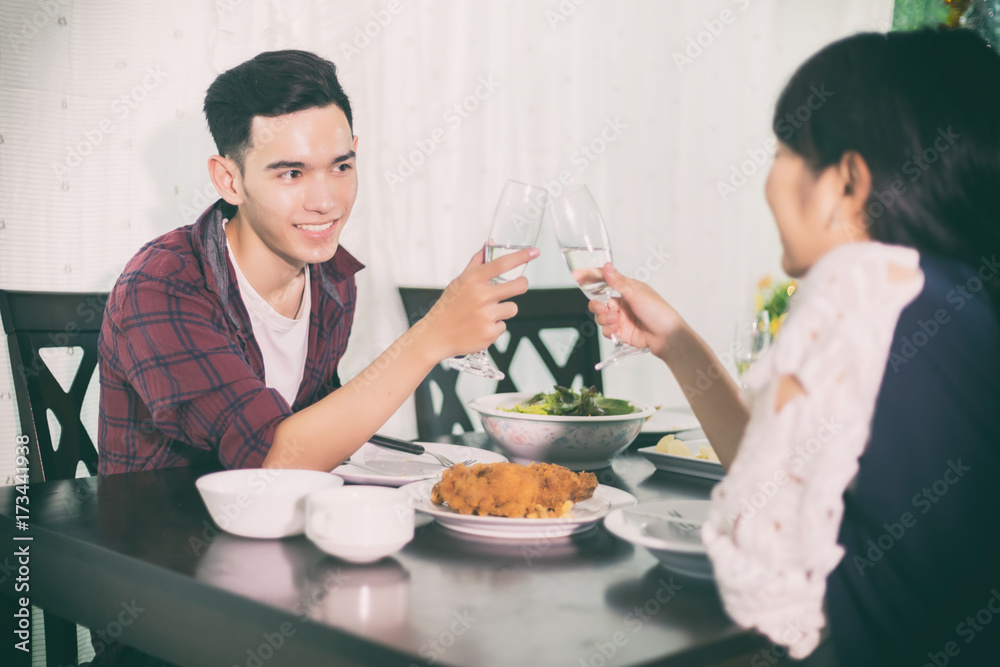 Asian young couple enjoying a romantic dinner evening drinks while sitting at the dinning table on the kitchen together Asian young couple enjoying a romantic dinner evening drinks while sitting at the dinning table on the kitchen together
