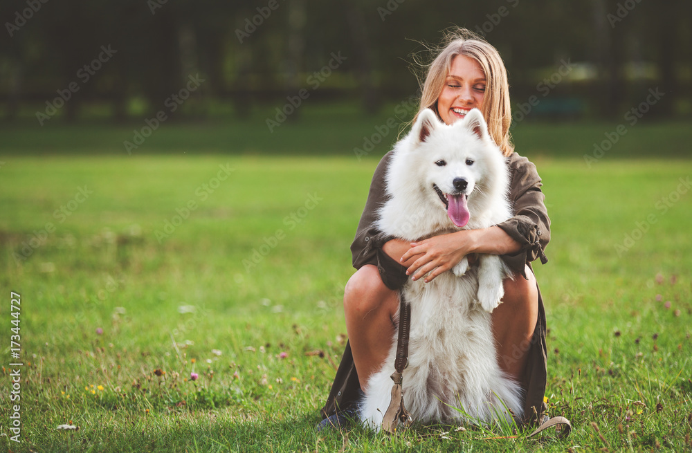 Pretty girl playing with her dog in the park, samoyed