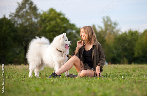 Pretty girl playing with dog on grass at the park