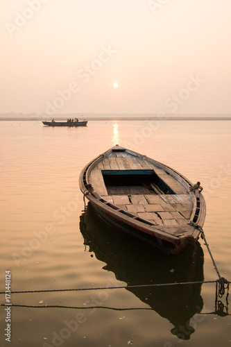 A boat in Ganges river, and another one further, while the sun is rising