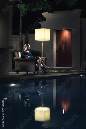 portrait of woman sitting in chair near swimming pool