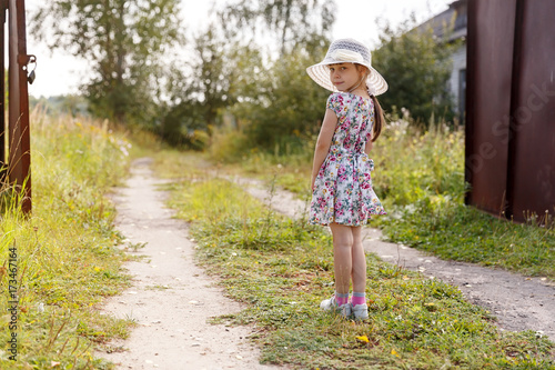 A little girl stands before an open gate © Yuriy Shurchkov