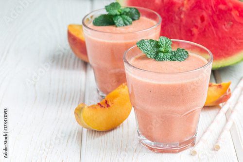 Watermelon  peach  mint and coconut milk smoothie in glass on white wooden background  horizontal  copy space