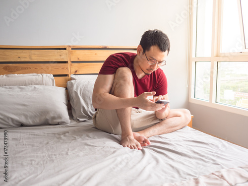 Lonely man playing his phone in his bedroom. photo