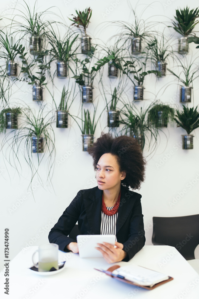 Confident and smiled cute Afro american business woman sitting in modern cafe and using her laptop or tablet. Confident and smiled cute Afro american business woman sitting in modern cafe and using her laptop or tablet.