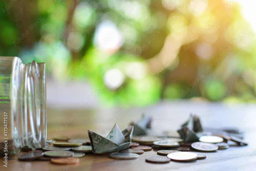 Close up dollar bird and coins in glass jar on wood table, color vintage style ,selective and soft focus