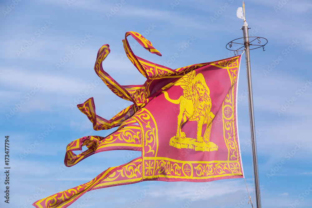 The Flag of Venice Venezia with the winged lion on blue sky background. The Flag of Venice Venezia with the winged lion on blue sky background.