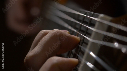 Close up of guitarist hand playing acoustic guitar. Close up shot of a man with his fingers on the frets of a guitar playing