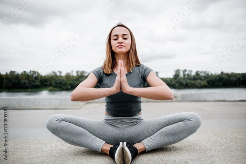 Yoga and meditation in a modern urbanistic city. Young attractive girl yoga meditating outdoors